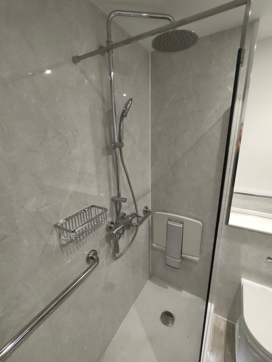 Close-up of the folding shower seat, grab rails, overhead and handheld shower