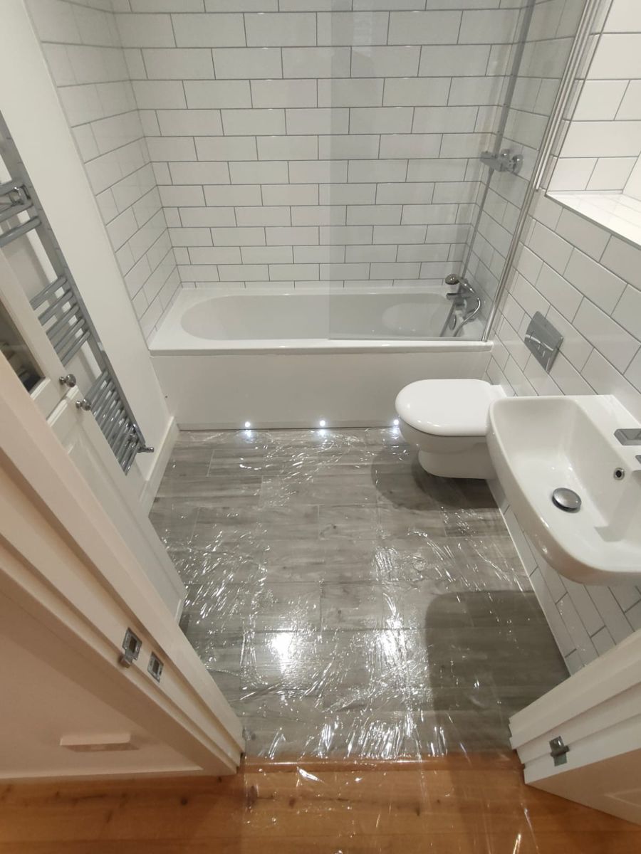 Before: bathroom from the doorway with a bath, glass bath screen, wall-hung toilet and basin